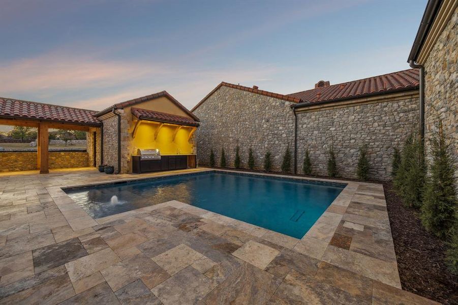 Pool at dusk with an outdoor pool, a patio area, and area for grilling