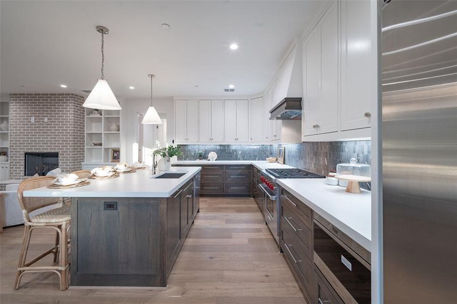 Kitchen with Sub Zero fridge, Wolf range stove, marble backsplash, 2 inch thick quartz countertops, and an island with sink.