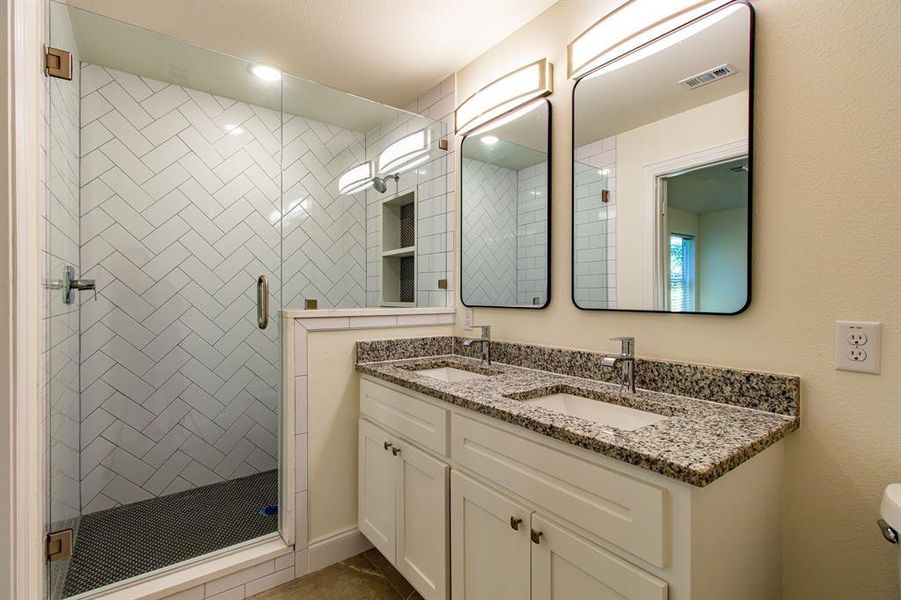 Bathroom featuring double vanity and a shower stall Bathroom featuring double vanity and a shower stall