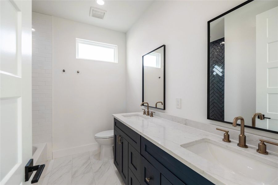 Full bathroom featuring double vanity, light marble finish floors, and bathing tub / shower combination