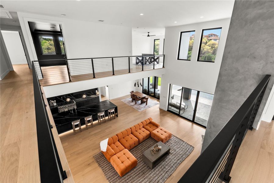 Living area featuring light wood-type flooring, recessed lighting, a ceiling fan, and a high ceiling Living area featuring light wood-type flooring, recessed lighting, a ceiling fan, and a high ceiling
