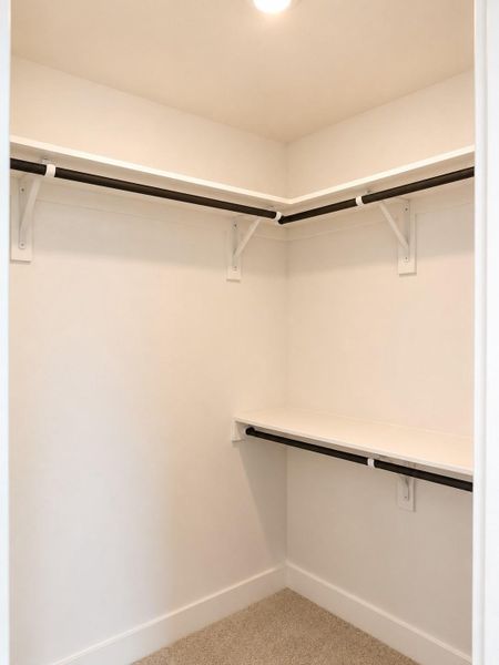 Spacious walk-in closet featuring built-in shelving, ample hanging space, and a clean modern design for optimal storage and organization Spacious walk-in closet featuring built-in shelving, ample hanging space, and a clean modern design for optimal storage and organization