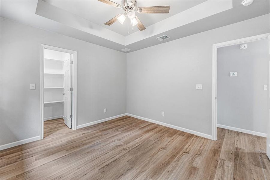 Empty room with a raised ceiling, ceiling fan, and baseboards Empty room with a raised ceiling, ceiling fan, and baseboards