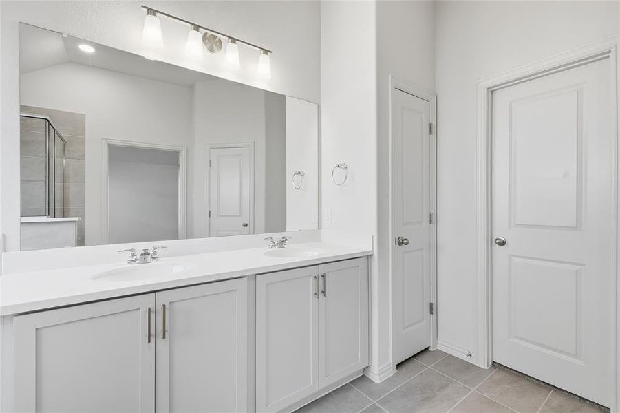 Full bath featuring double vanity, light tile patterned floors, a closet, and a walk in shower Full bath featuring double vanity, light tile patterned floors, a closet, and a walk in shower