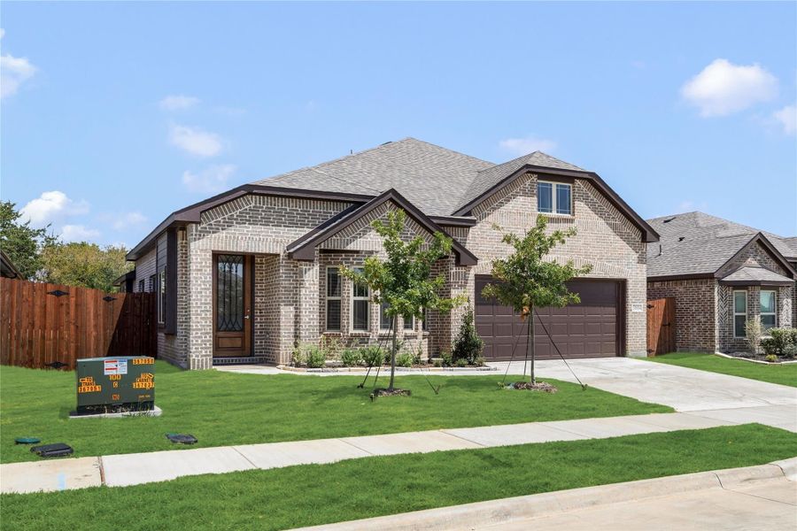 Single-story brick home with two-car garage, arched entry, and manicured front lawn in a suburban neighborhood.