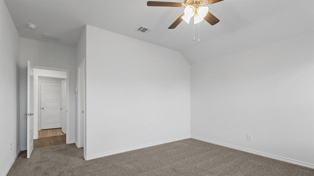 Spare room featuring ceiling fan, carpet floors, and lofted ceiling