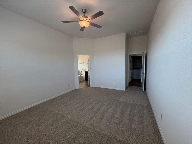 Unfurnished bedroom featuring light colored carpet, a ceiling fan, and ensuite bathroom