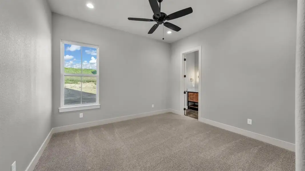 Carpeted interior space with a ceiling fan, recessed lighting, and a window with a white frame Carpeted interior space with a ceiling fan, recessed lighting, and a window with a white frame