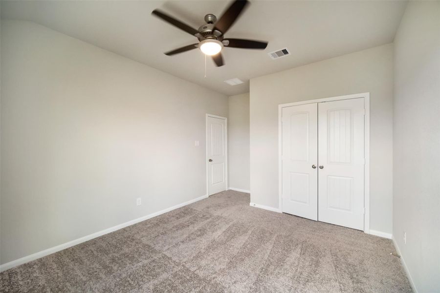 Secondary bedroom features plush carpeting, large windows that let in plenty of natural light, bright paint, and spacious closets.Sample photo of completed home with similar floor plan. Actual colors and selections may vary.