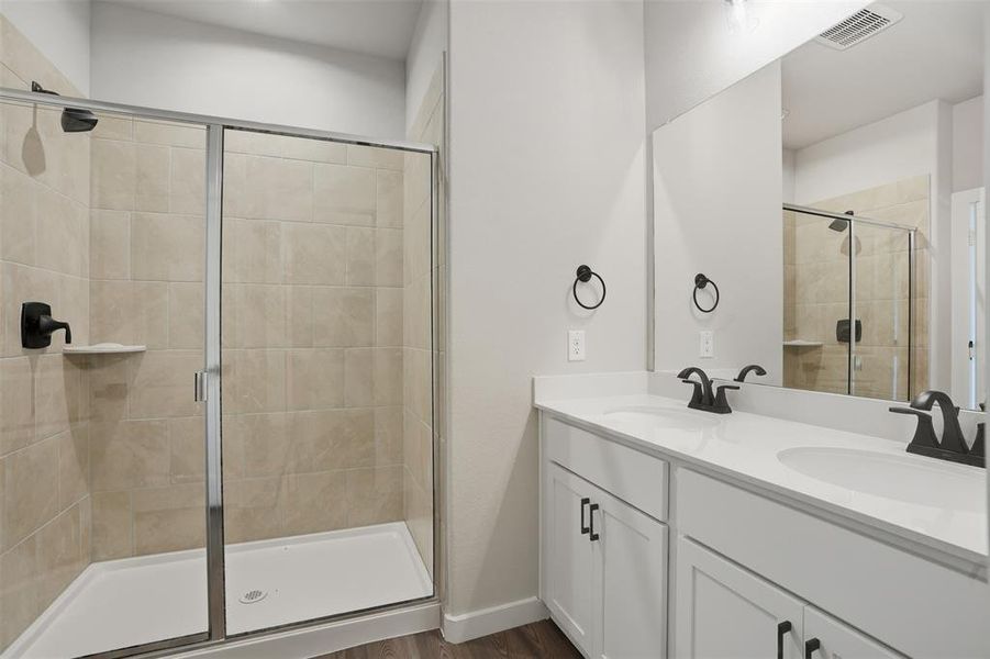 Bathroom with a shower stall, double vanity, and dark wood-style flooring Bathroom with a shower stall, double vanity, and dark wood-style flooring