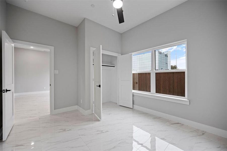 Unfurnished bedroom featuring baseboards, marble finish floor, a closet, and ceiling fan