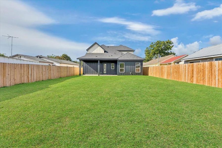 Back of house with a patio, roof with shingles, and a fenced backyard