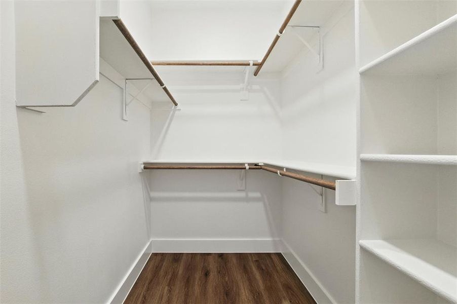 Walk in closet with dark wood-type flooring
