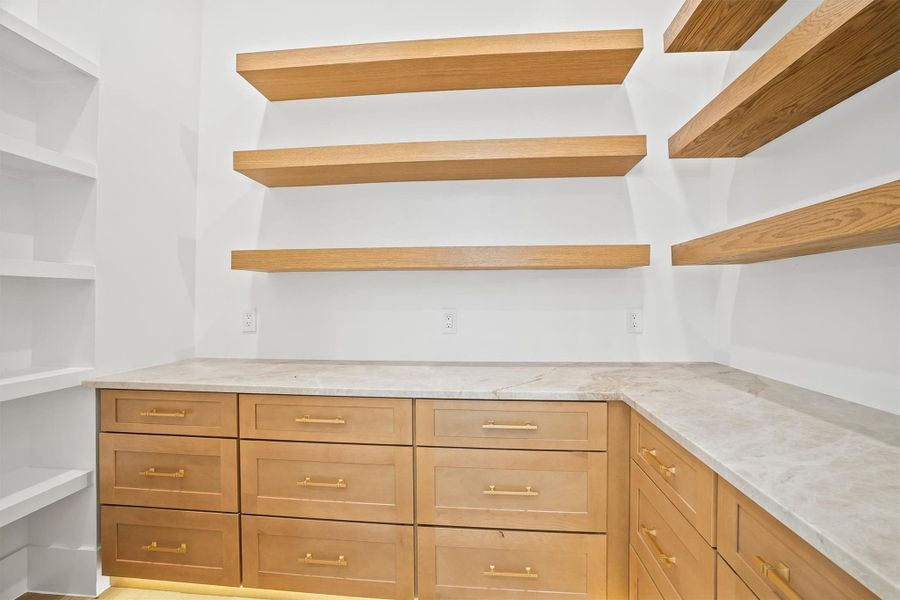 The walk in pantry has plenty of storage and floating shelves right above your countertops!