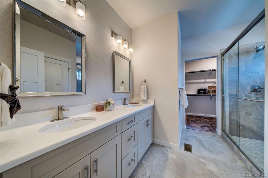 Bathroom has dual vanity, drawers, and a large shower.