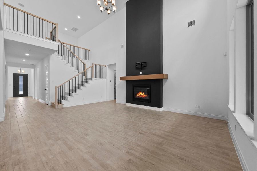 Bright and spacious living room featuring a dramatic black accent fireplace and views into the gourmet kitchen.