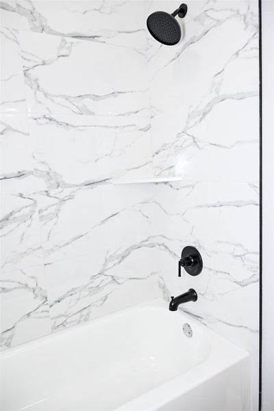 Bathroom featuring a combined bath / shower with marble appearance