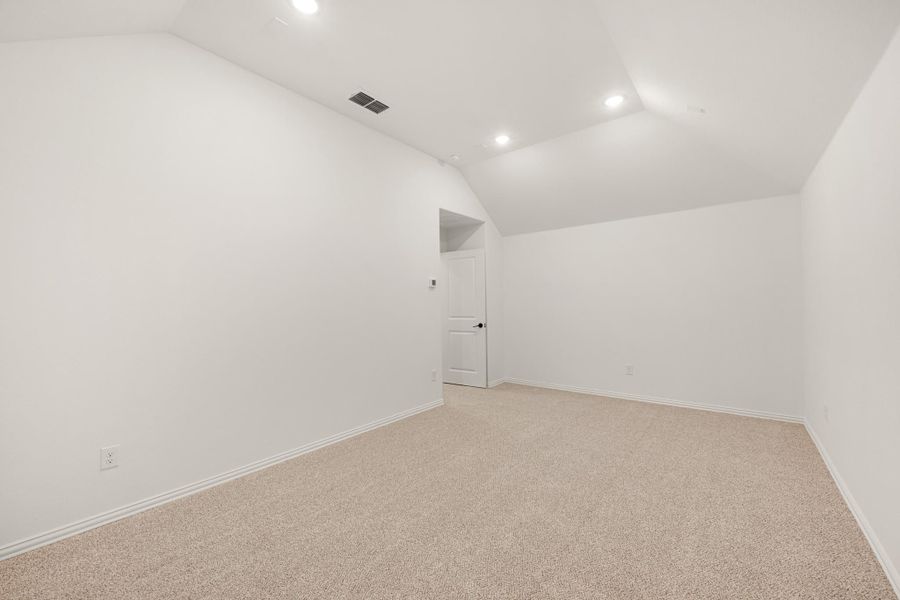 Empty room with vaulted ceiling, recessed lighting, beige carpet, and white walls