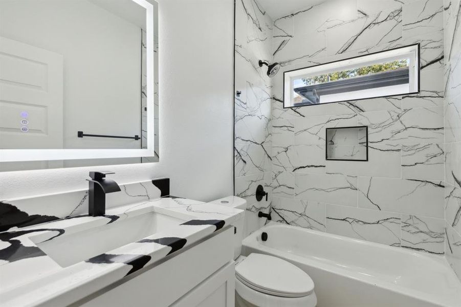 Full bathroom with tiled shower / bath, vanity, and toilet