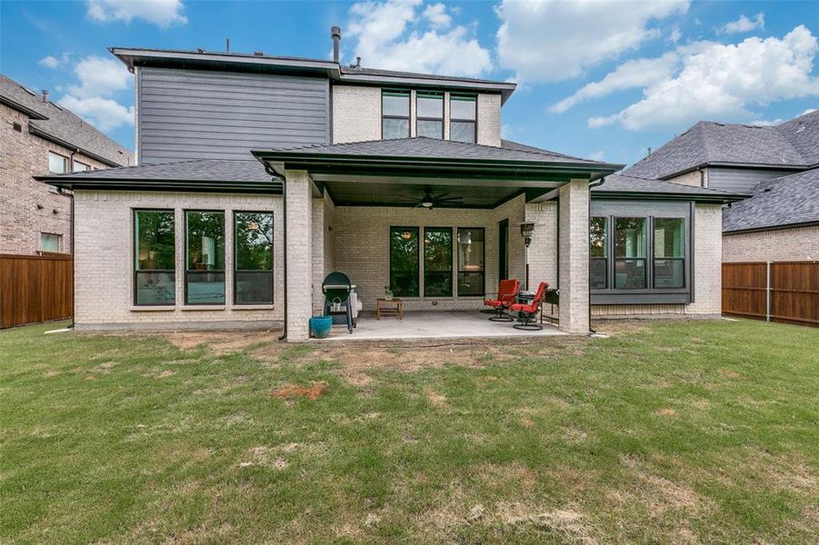 Rear view of property featuring ceiling fan, a lawn, and a patio