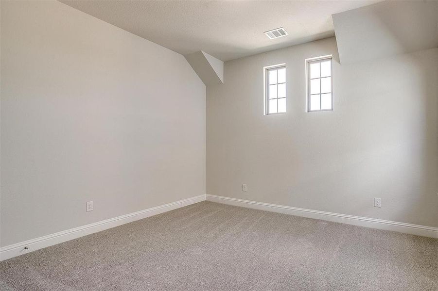 Additional living space with light colored carpet and baseboards