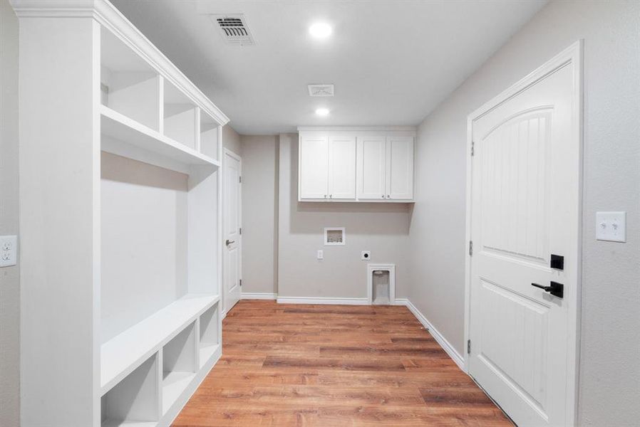 Washroom featuring washer hookup, electric dryer hookup, and light hardwood / wood-style flooring Washroom featuring washer hookup, electric dryer hookup, and light hardwood / wood-style flooring