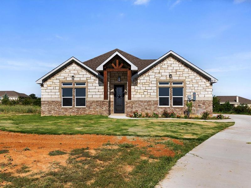 View of front of property featuring a front lawn, stone siding, and brick siding