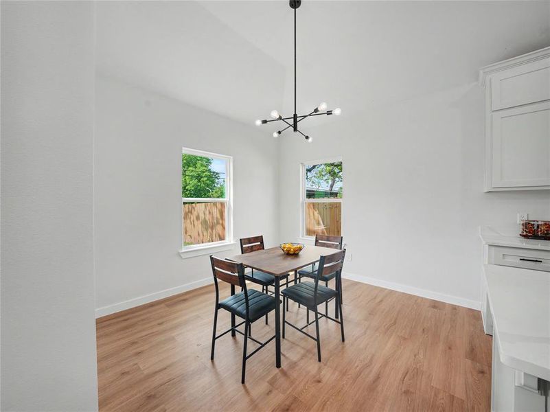 Dining space featuring light wood finished floors, hanging lights, and vaulted ceiling