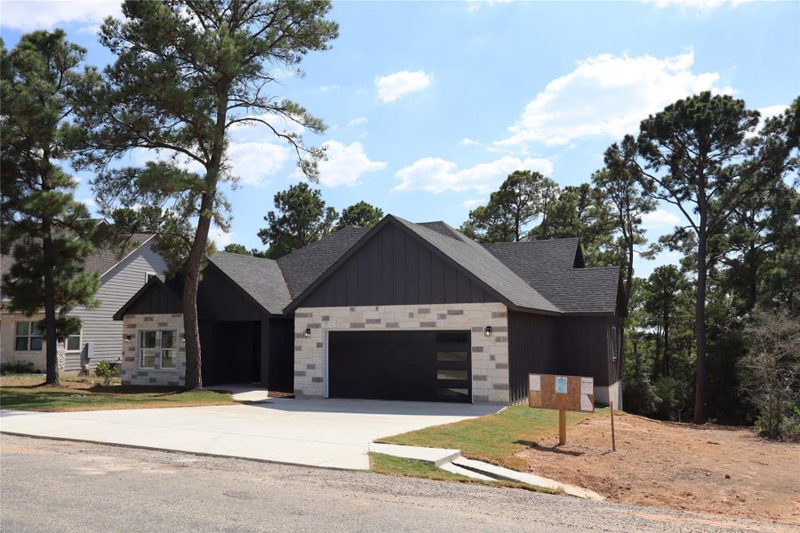 View of front of property featuring board and batten siding, concrete driveway, roof with shingles, and an attached garage