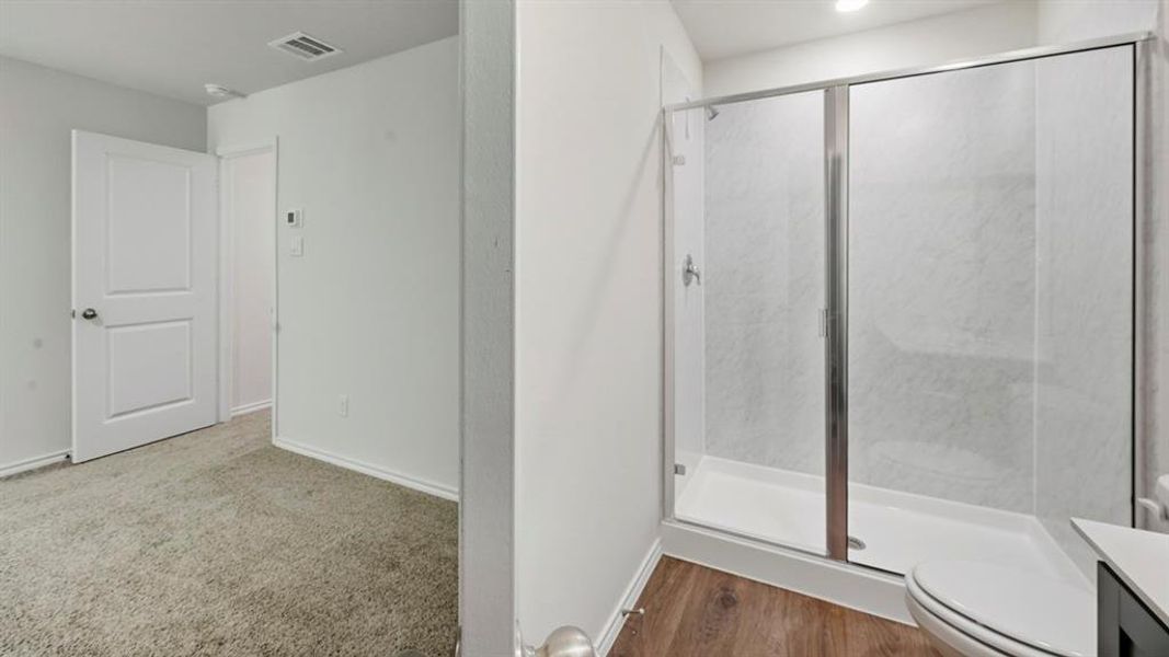 Bathroom featuring a stall shower, wood finished floors, and carpet floors