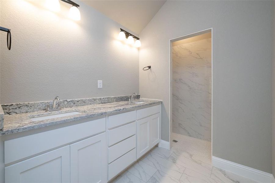 Bathroom with lofted ceiling, tile patterned floors, and double sink vanity