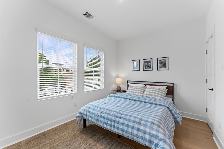 This secondary bedroom on the second floor exudes warmth and sophistication with its rich engineered hardwood flooring, adding a touch of elegance to the space. The smooth, durable surface enhances the room’s clean lines and complements a variety of décor from cozy and traditional to sleek and modern. Natural light dances across the wood grain, creating a serene atmosphere ideal for rest, work, or creative pursuits.