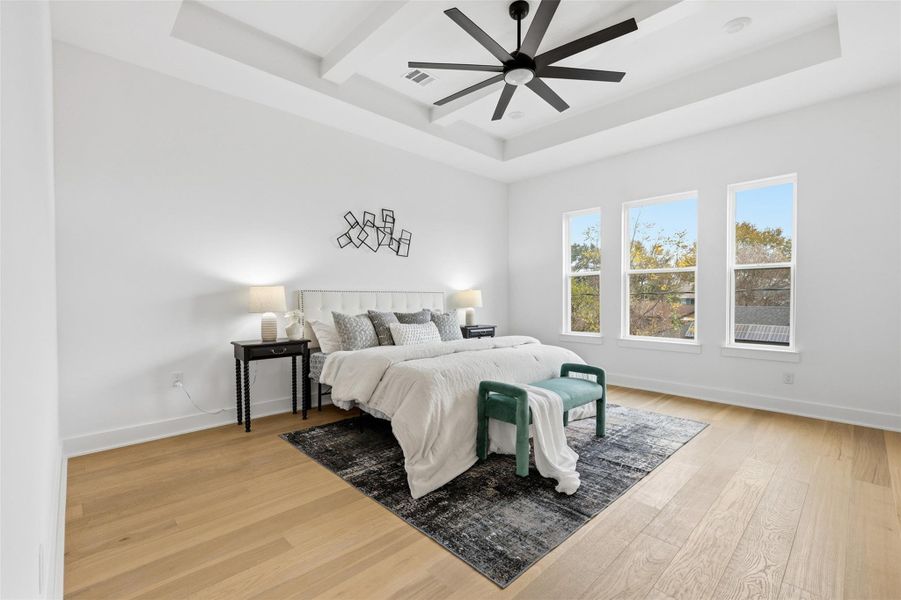 An oversized primary bedroom highlighted by beamed ceilings and a statement ceiling fan for comfort and scale.