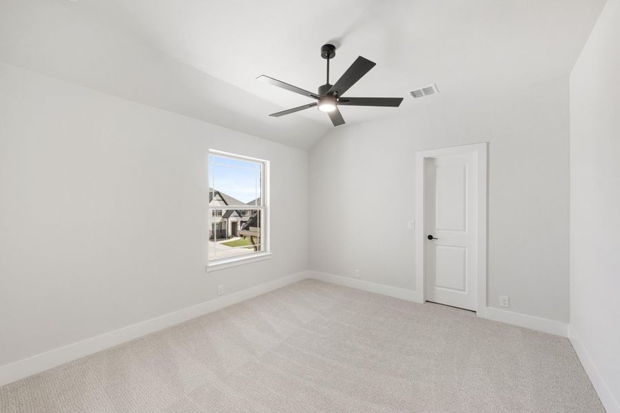 Empty bedroom with vaulted ceiling, black ceiling fan, carpet flooring, and a single window
