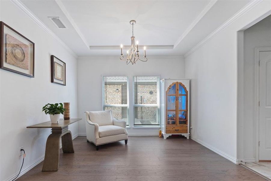 Living area featuring hardwood / wood-style floors, crown molding, a chandelier, and a tray ceiling