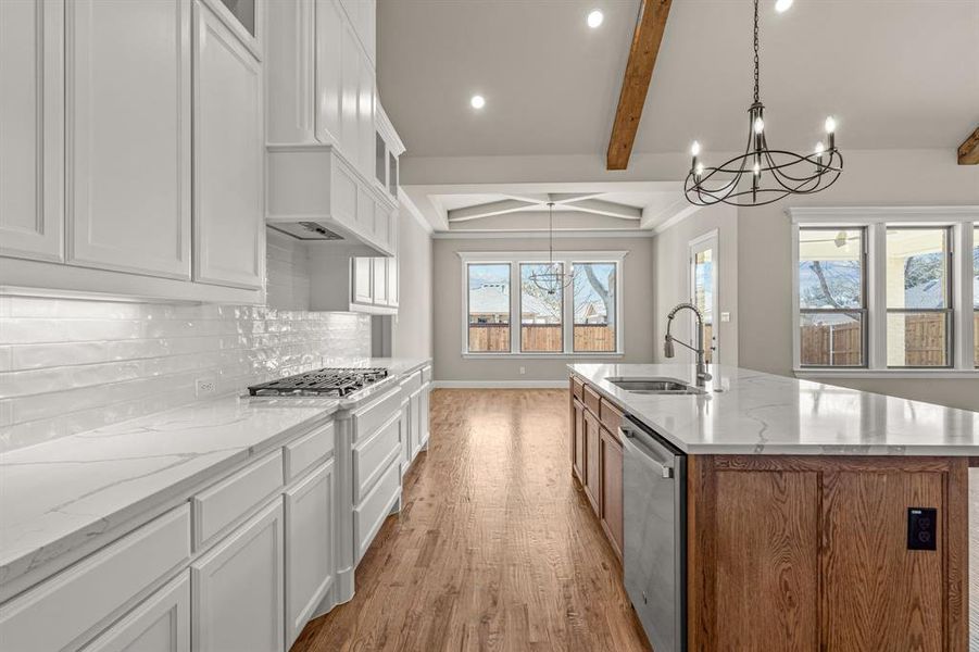 Kitchen with a kitchen island with sink, sink, stainless steel appliances, and white cabinets