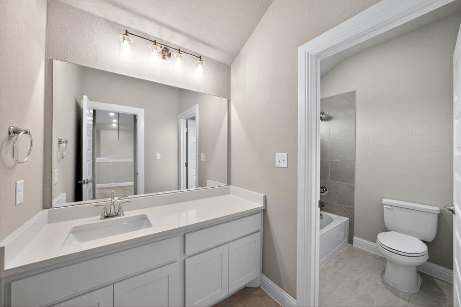 Full bath with vanity, shower / tub combination, a textured wall, and light tile patterned flooring Full bath with vanity, shower / tub combination, a textured wall, and light tile patterned flooring