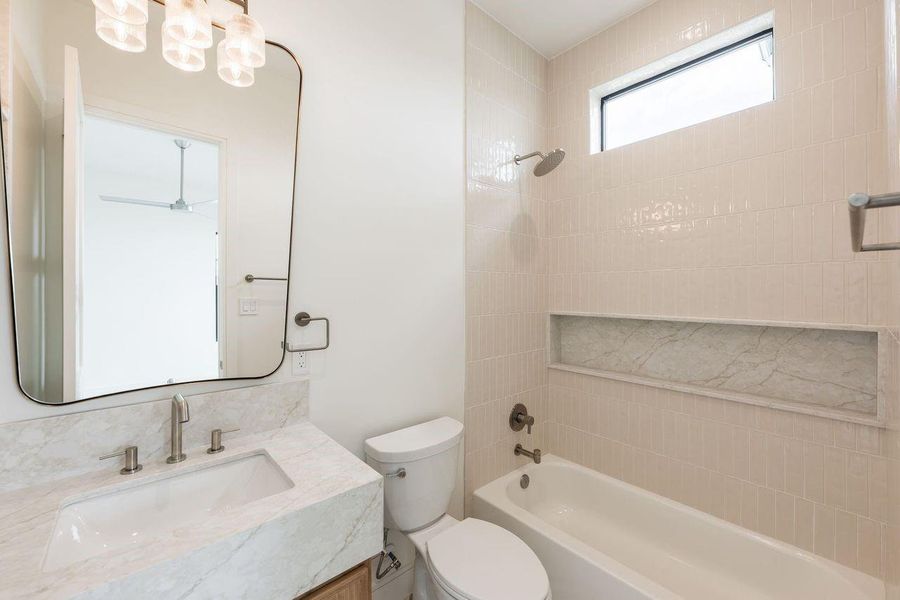 The most memorable spaces are often defined by their details. Here, a monolithic stone vanity, soft-textured tile, and designer-selected fixtures come together in a palette that feels quietly sophisticated and effortlessly timeless.