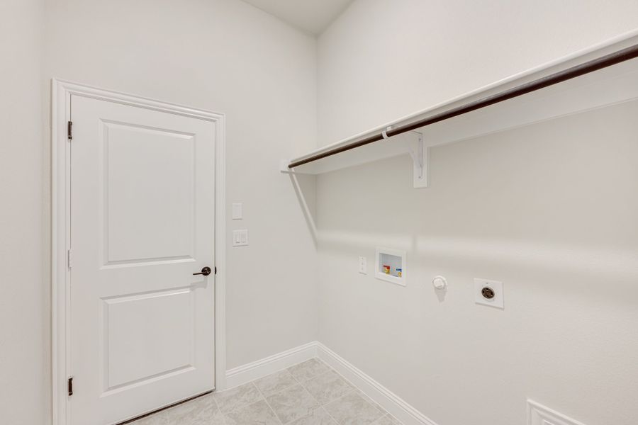 Laundry room with wall-mounted shelf, hanging rod, washer and dryer hookups, and tile floor