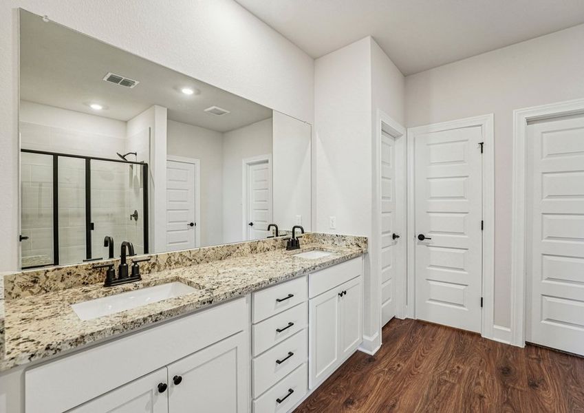 Primary bathroom featuring a double vanity with granite countertop and a large mirror. Primary bathroom featuring a double vanity with granite countertop and a large mirror.