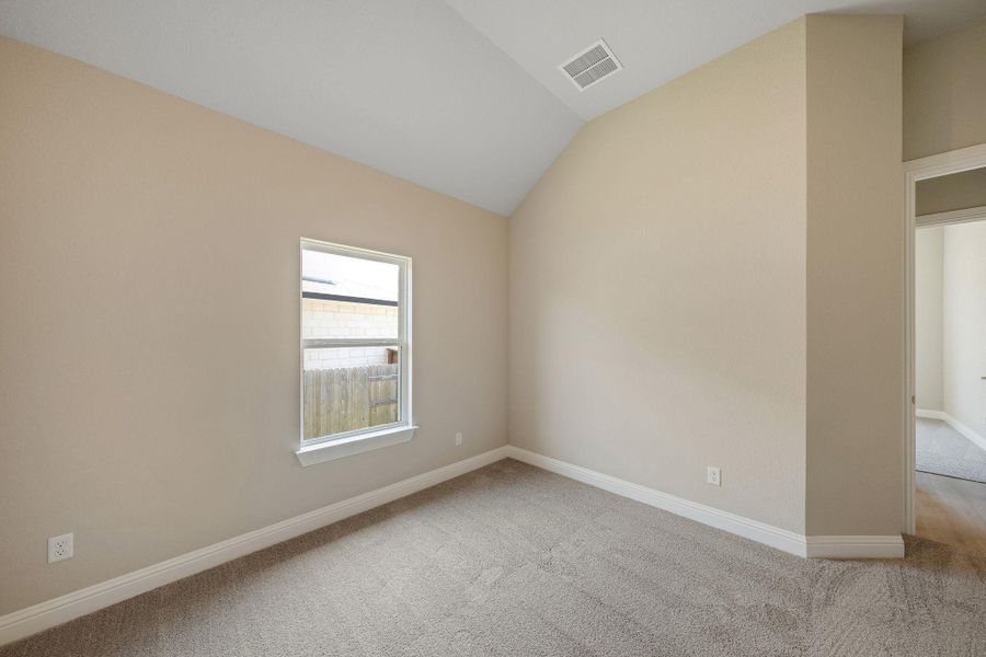 Carpeted empty room with lofted ceiling and baseboards