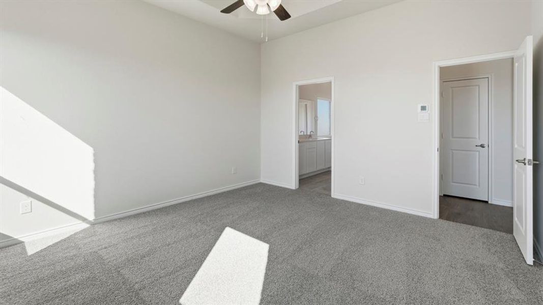 This room features light gray carpeting, white walls, and a ceiling fan This room features light gray carpeting, white walls, and a ceiling fan