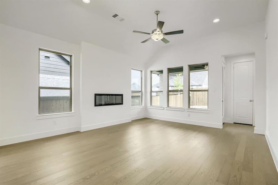 Spacious living area featuring a vaulted ceiling with a ceiling fan, recessed lighting, and light wood-finish flooring