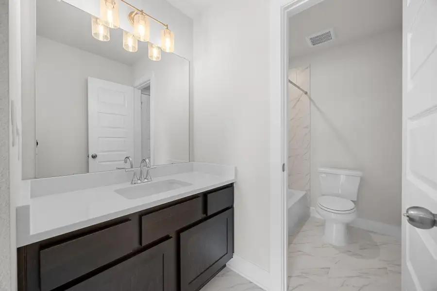 Bathroom featuring marble finish flooring, vanity, and shower / bath combination