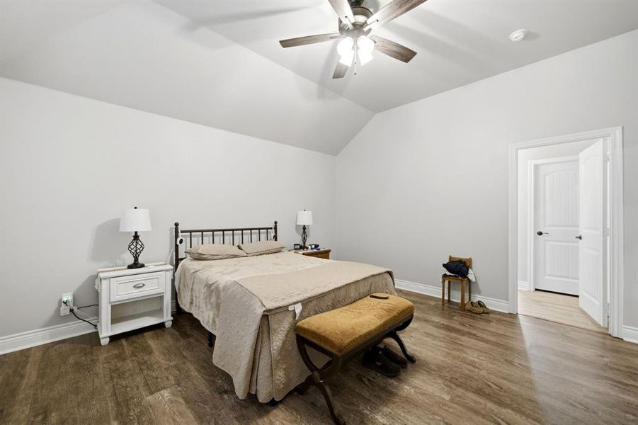 Bedroom with vaulted ceiling, dark wood finished floors, and a ceiling fan