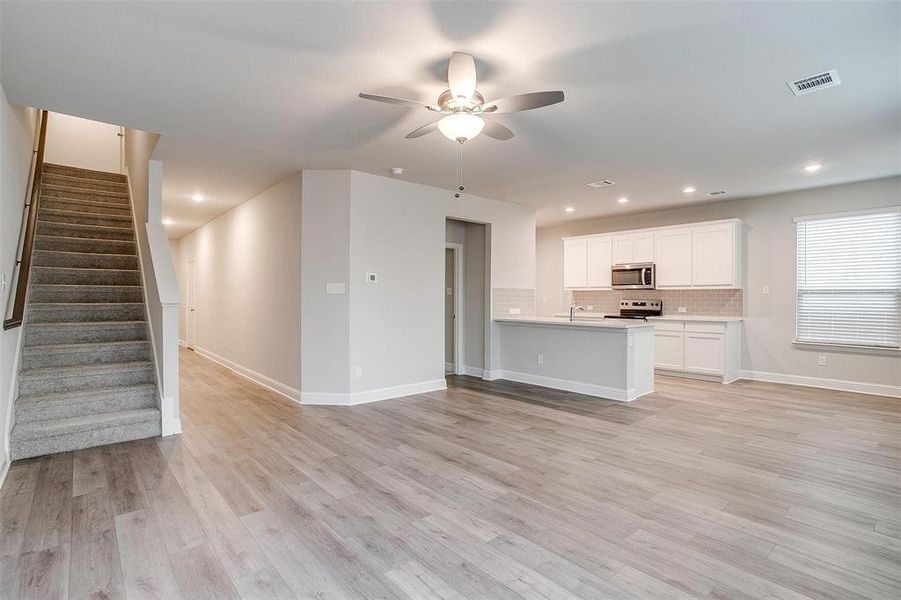 Unfurnished living room featuring ceiling fan, sink, and light hardwood / wood-style floors