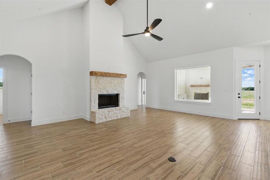 Unfurnished living room with arched walkways, high vaulted ceiling, a fireplace, wood finish floors, and beamed ceiling Unfurnished living room with arched walkways, high vaulted ceiling, a fireplace, wood finish floors, and beamed ceiling