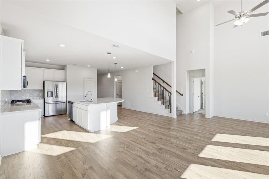 Kitchen with white cabinets, an island with sink, appliances with stainless steel finishes, decorative light fixtures, and recessed lighting