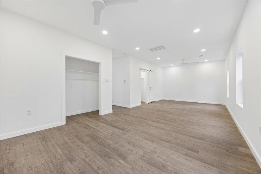 A spacious, naturally illuminated room features durable wood flooring and modern ceiling fixtures.