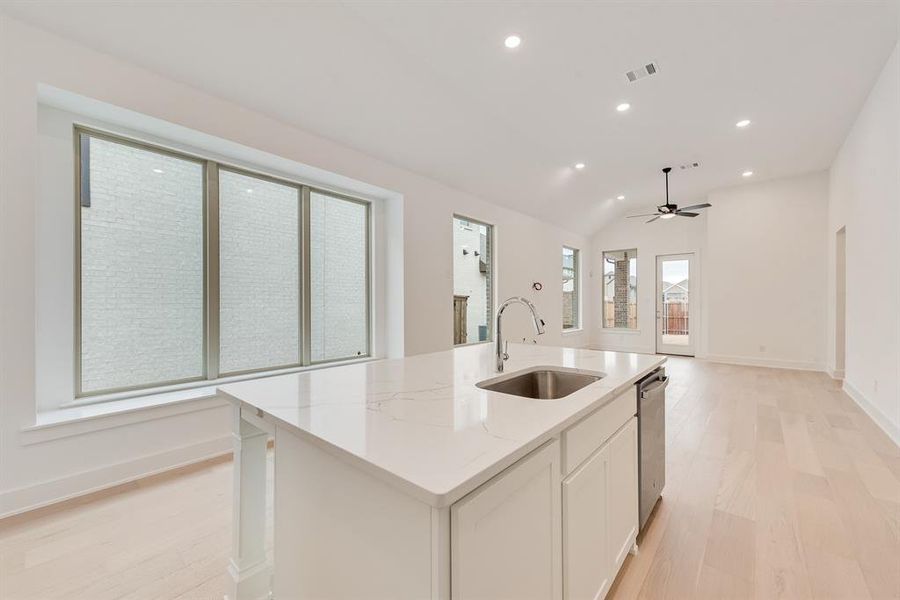 Kitchen featuring recessed lighting, light wood-style flooring, white cabinets, light stone counters, and a center island with sink Kitchen featuring recessed lighting, light wood-style flooring, white cabinets, light stone counters, and a center island with sink